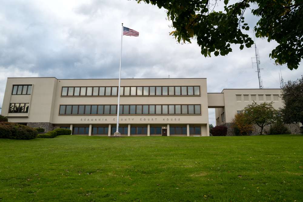 The Skamania County Courthouse in Stevenson, Washington, with its classic architecture set against a backdrop of trees and clouds.