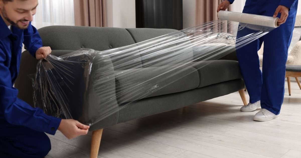 Two movers in Oatfield, OR wrapping cling film around a couch