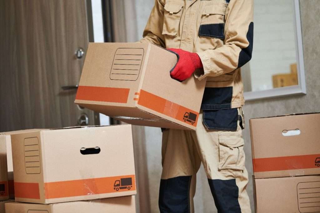 Cumings movers in a tan jumpsuit carrying a box