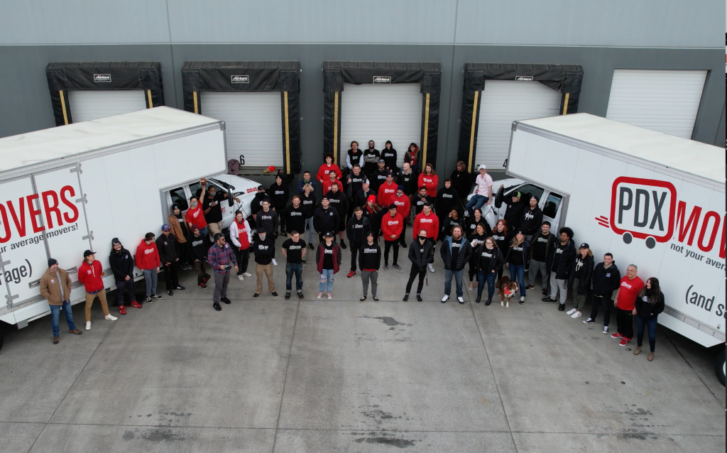 Aerial view of the entire PDX Movers team standing by company trucks