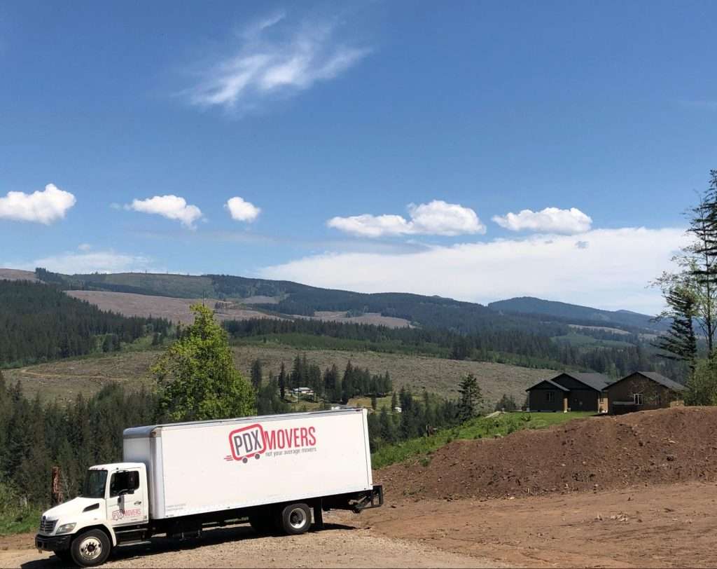 PDX Movers truck parked on dirt road with rolling hills in the background