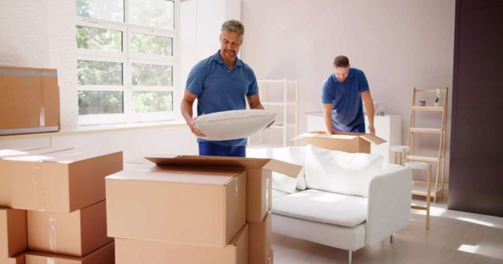 Two furniture movers with a Memorial moving company packing furniture and bedding