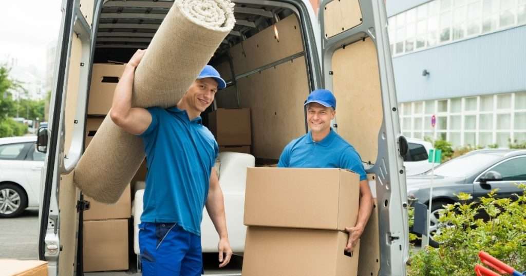 Two professional movers from a moving company in Memorial TX holding boxes and rugs